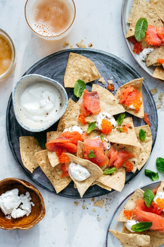 Tortilla chips served with smoked trout, cheese and trout caviar on a blue plate. Recipe development, food photography and styling by Chiara Gianelli.