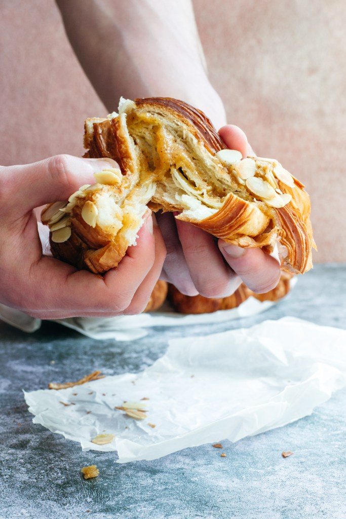 Hands holding a croissant.
