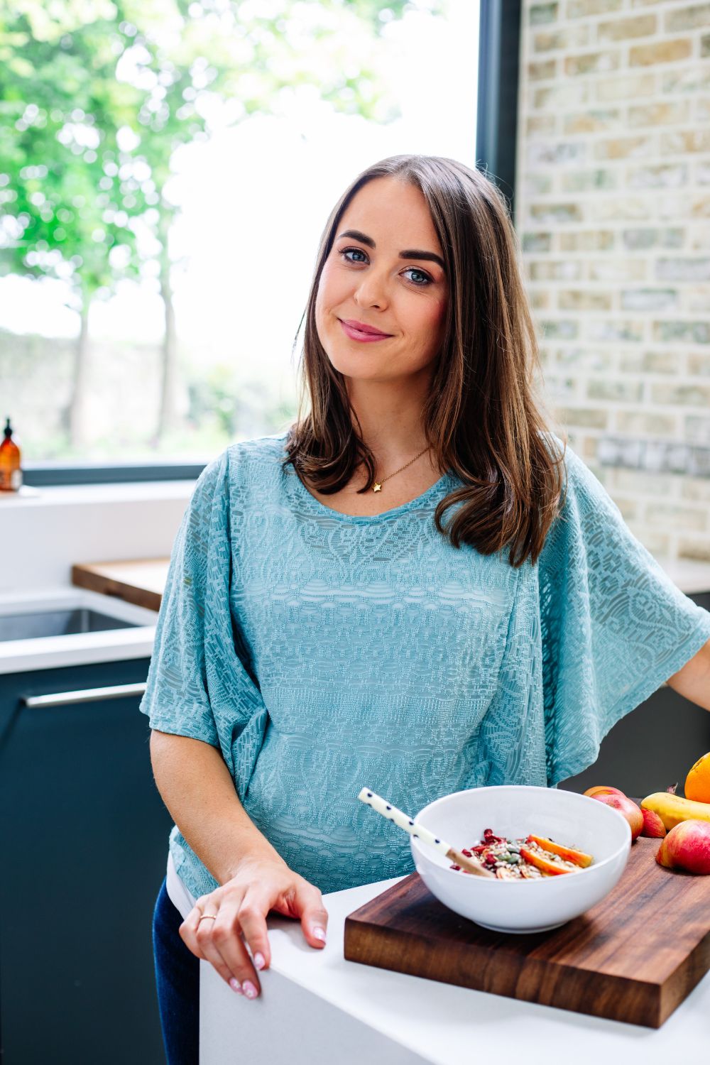 Woman wearing a blue shirt standing cooking breakfast in a kitchen. Brand photography session by Chiara Gianelli