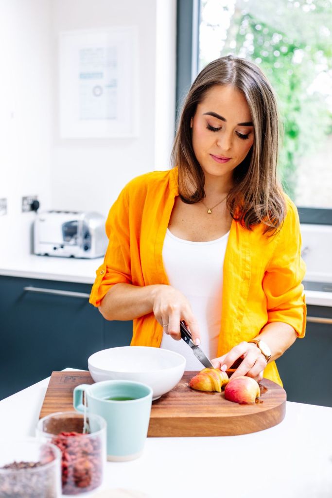 Woman wearing an orange shirt and preparing her breakfast. Brand photography by Chiara Gianelli