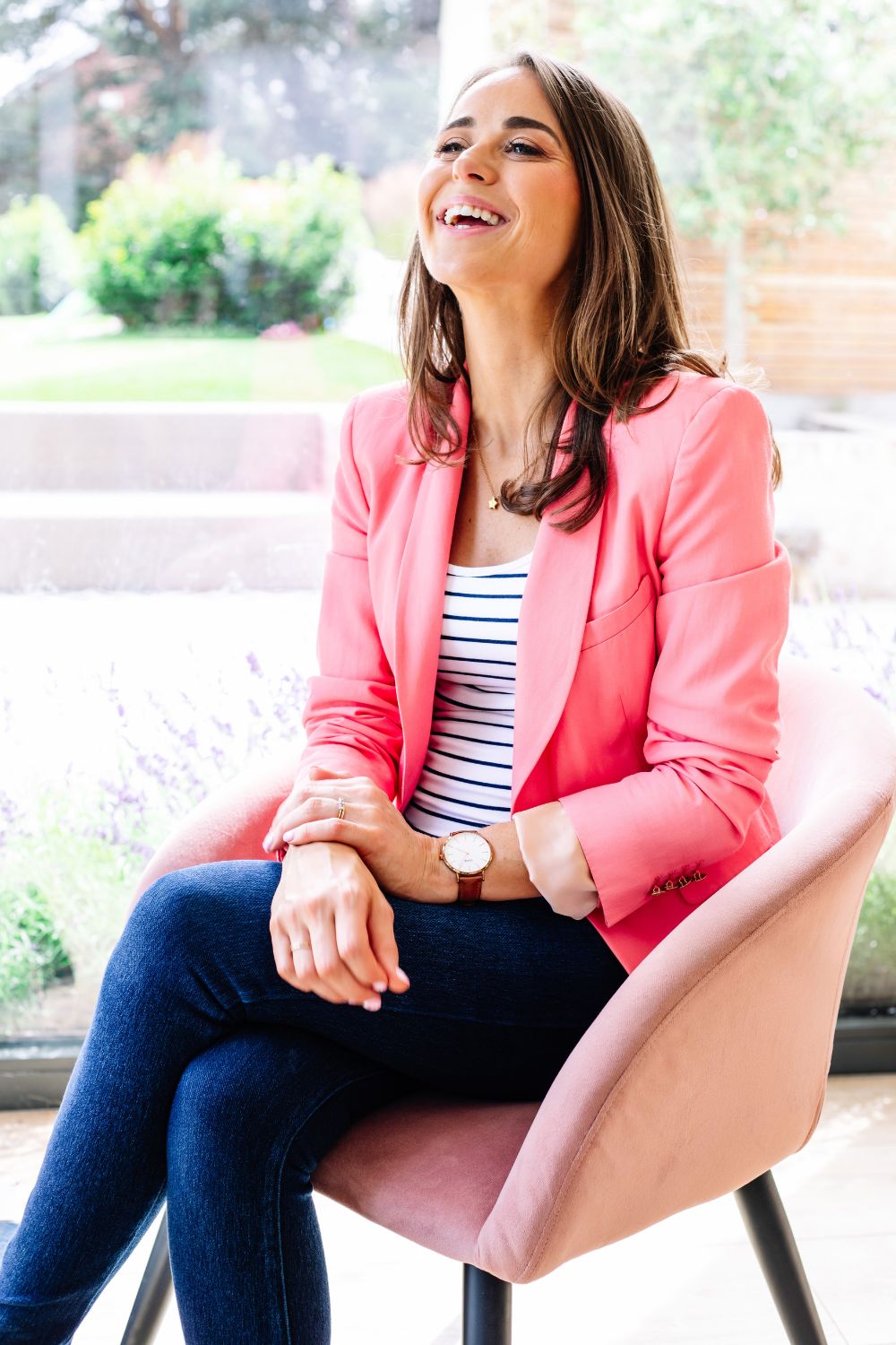 Woman wearing a pink blazer sitting in a pink chair