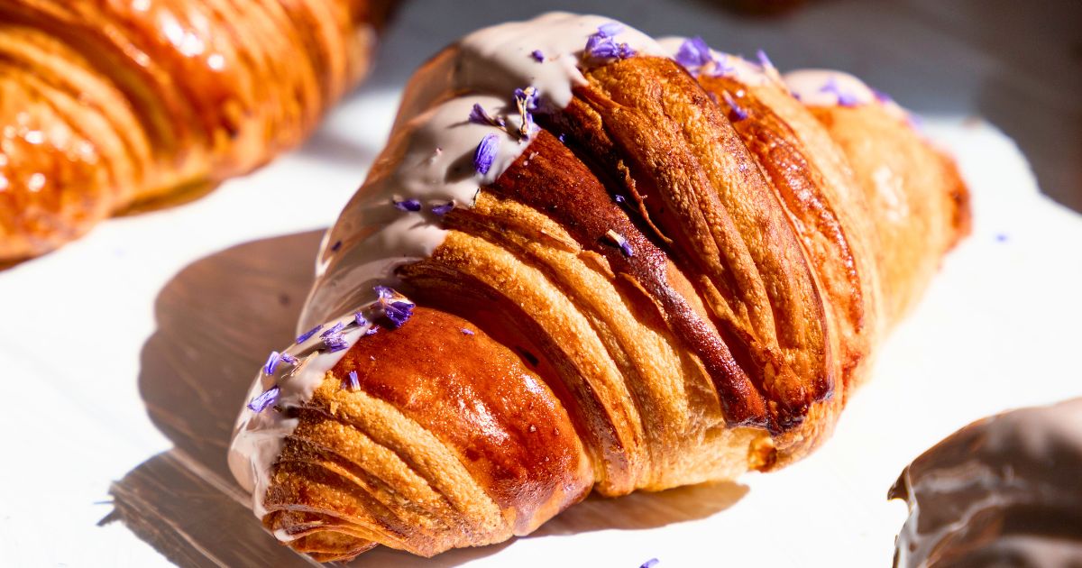 Decorative photo of a croissant with a white glaze on a white table