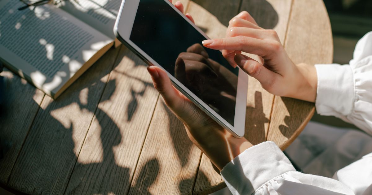 Decorative image of a woman wearing a white shirt working on a tablet outdoor.